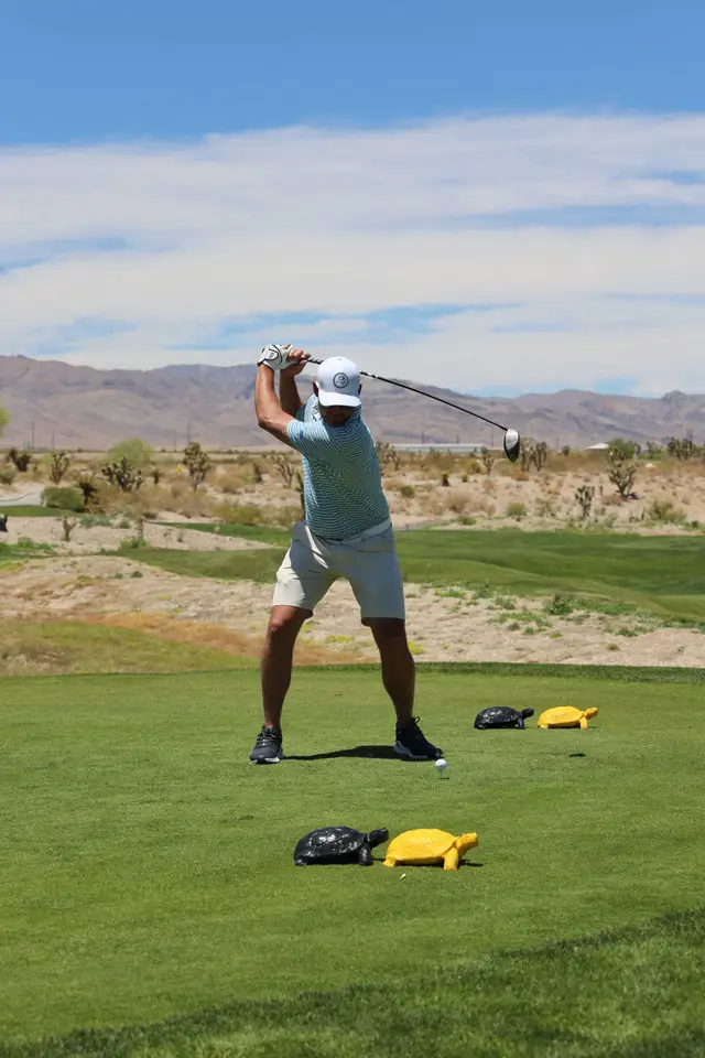 Golfer at the top of his backswing beside the turtle tee markers